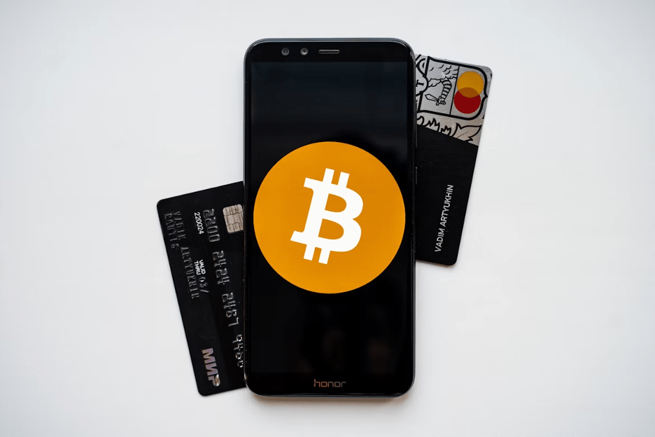A smartphone displaying the Bitcoin logo, surrounded by bank cards that are popular options at casinos featured by Nightrush
